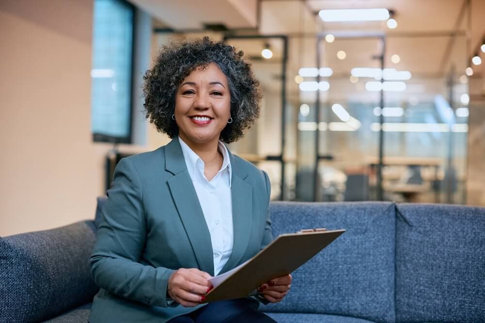 Confident insurance professional holding client documents, representing the communication, expertise, and professionalism required to become a successful insurance agent.